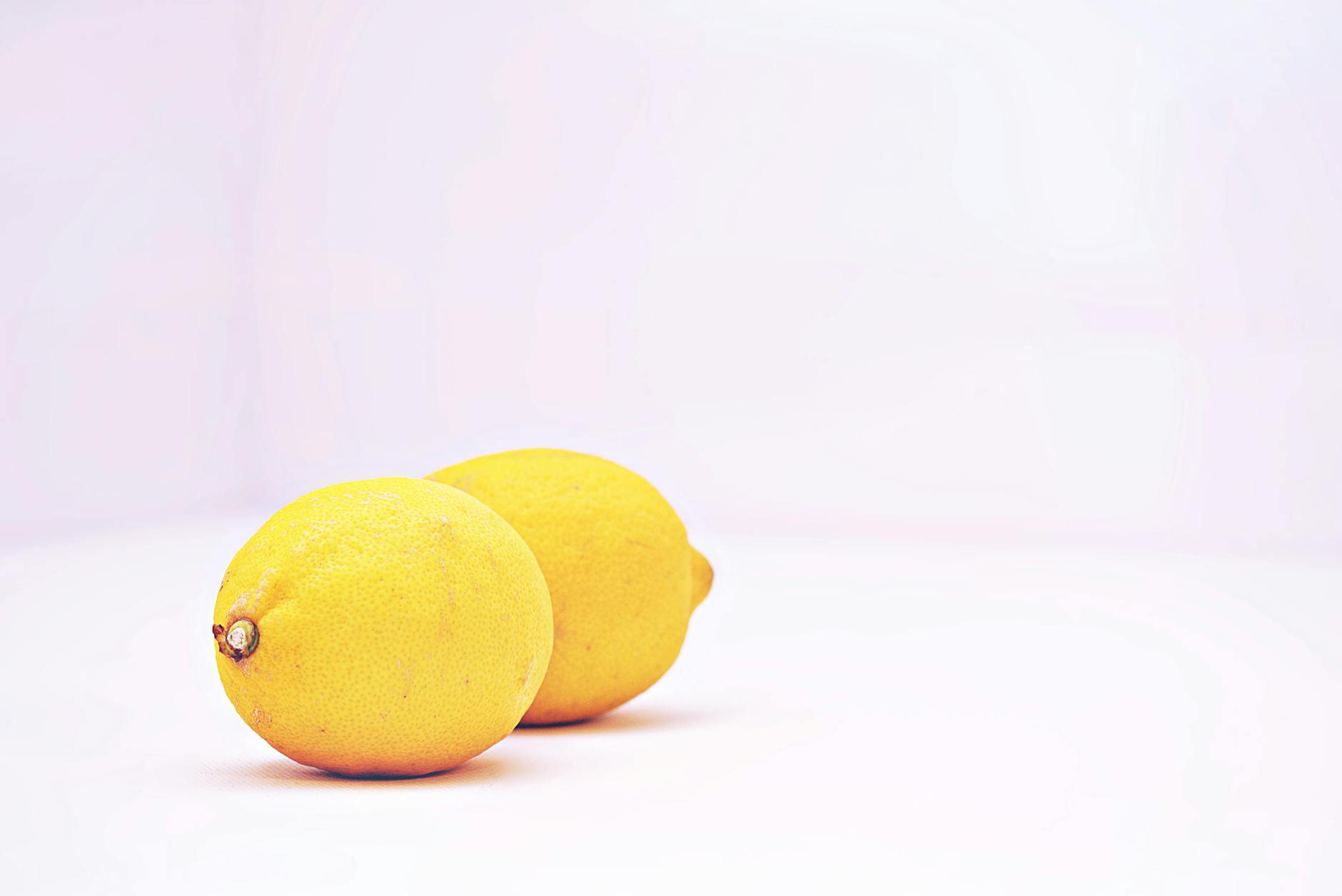 Two fresh lemons on a minimalistic white background representing safe, natural pleasure