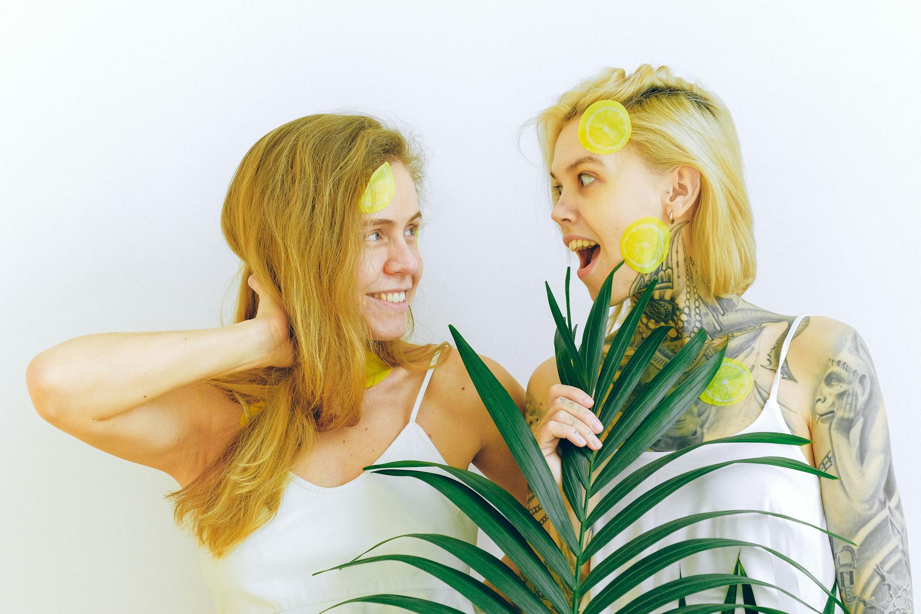 Two women smiling with lemon slices, expressing joy and confidence in pleasure