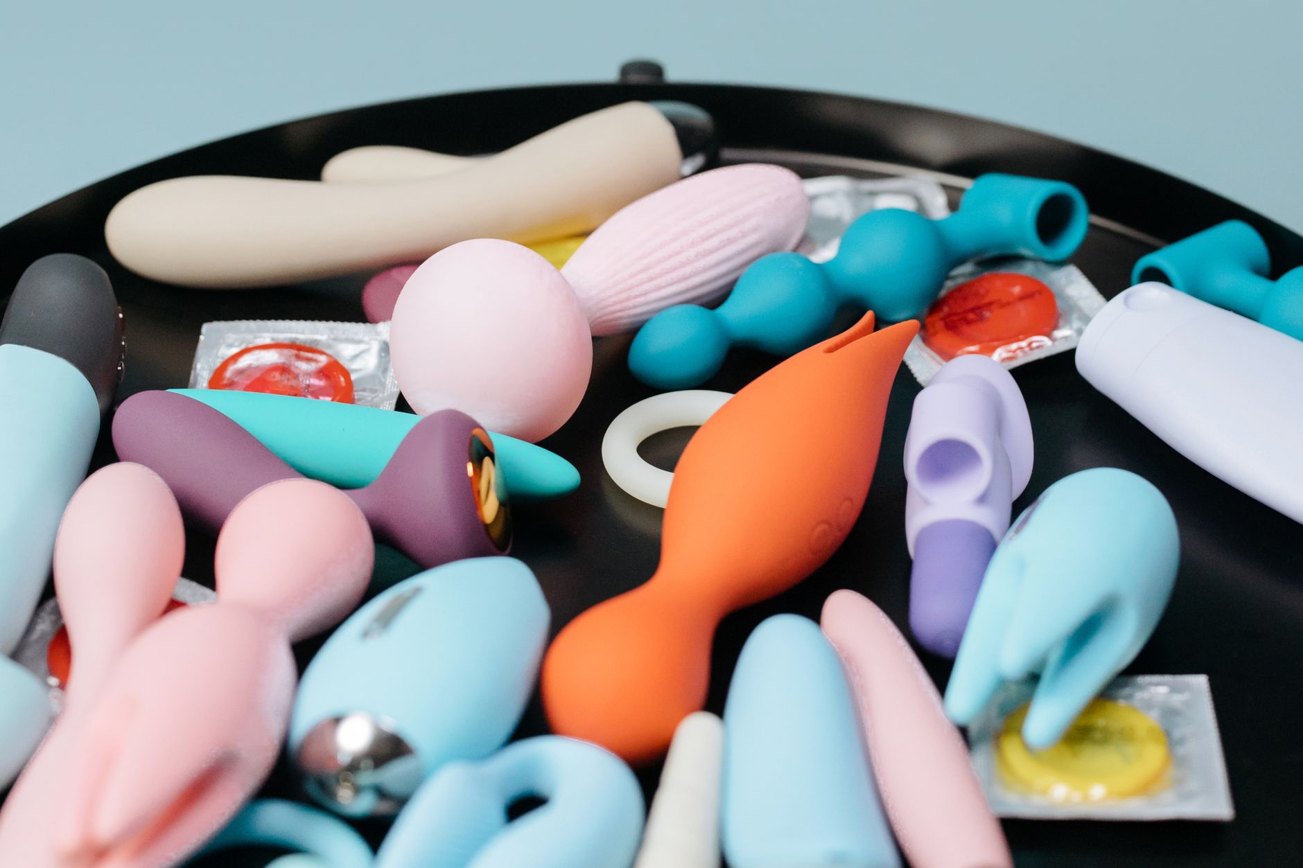 A collection of colorful vibrators and intimate wellness toys arranged on a black surface.