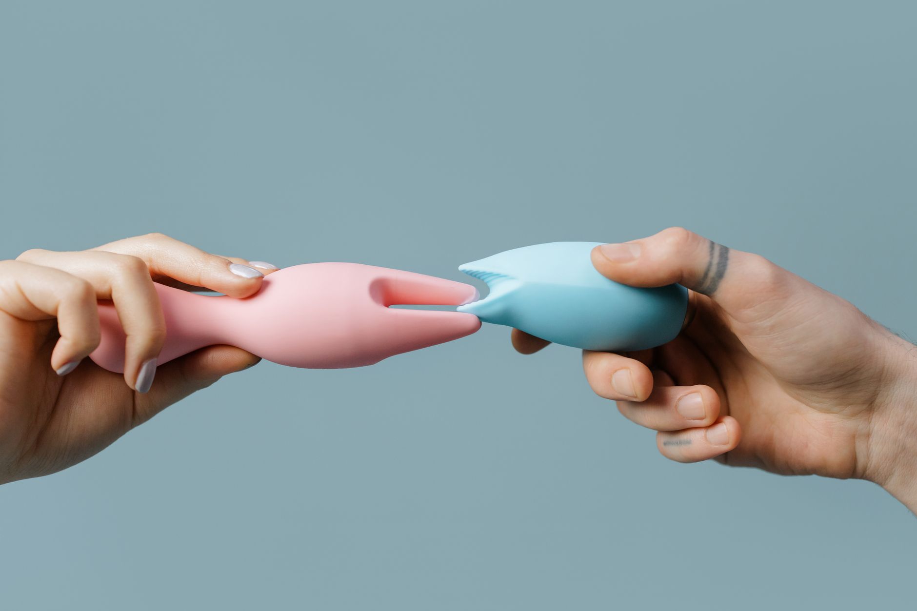 Nahaufnahme einer Hand, die einen blauen Vibrator gegen einen gestrickten Pullover hält