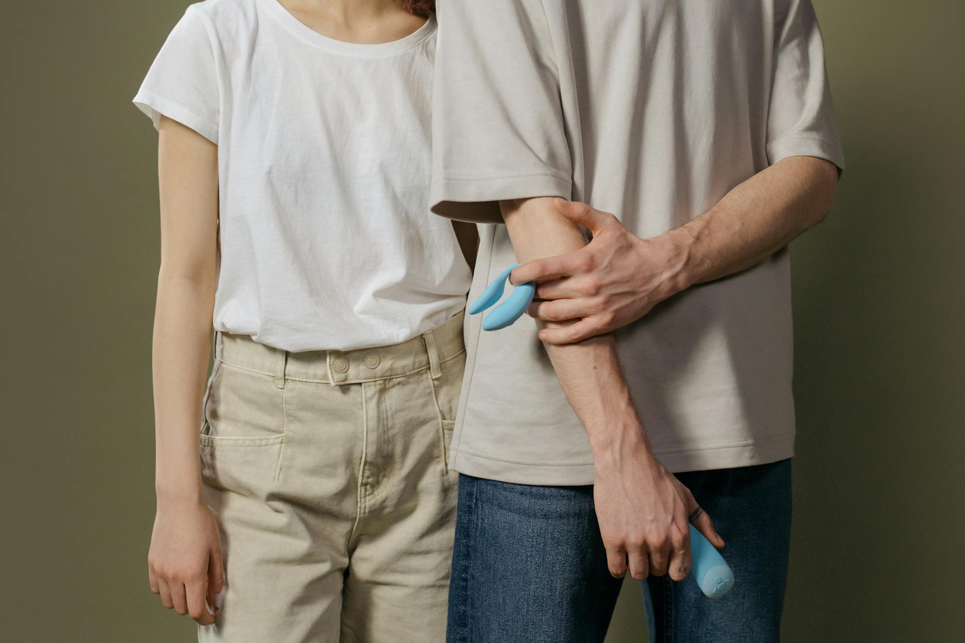 Ein junges Paar steht zusammen, hält einen eleganten Vibrator und symbolisiert moderne Intimität
